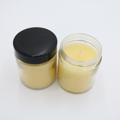 La mano profumata della candela del barattolo di vetro giallo della verbena del limone ha versato le candele della soia con il coperchio nero